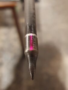 Plaats de laser op de punt van de pijl. Het is best om dit helemaal op het uiteinde van de pijl te doen. Pas de links/recht positie van de arrow rest aan totdat de laser perfect in het midden van de pijl ligt. Je zal zien dat wanneer je de oplegger vast schroeft, dat de positie iets zal veranderen. Hou daar rekening mee en zorg dat de laser perfect in het midden is wanneer de arrow rest vast geschroefd is. Dit kan betekenen dat de laser voor het vastschroeven misschien iets meer naar rechts moet liggen en dat tijdens het vastschroeven de laser op de juiste positie komt. Doe indien nodig het licht uit zodat je heel goed kan zien waar de laser schijnt.