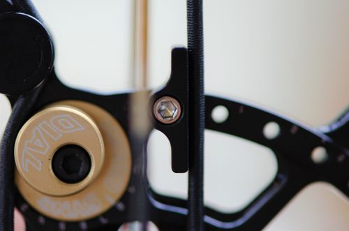 Door gebruik te maken van de micro sync dails van de Bowtech BT-X kan je de timing perfect krijgen. Deze stopper is een aangepast model om een hardere muur te creëren. Je ziet het effect van de micro dail... deze duwt de kabel, links op de foto, een beetje verder en maakt die zo effectief korter.